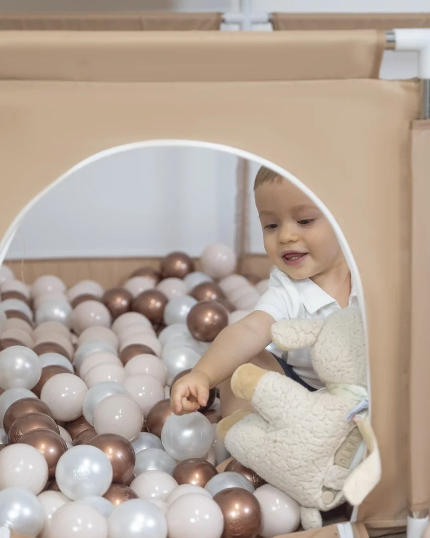 Baby im Laufgitter mit Bällen