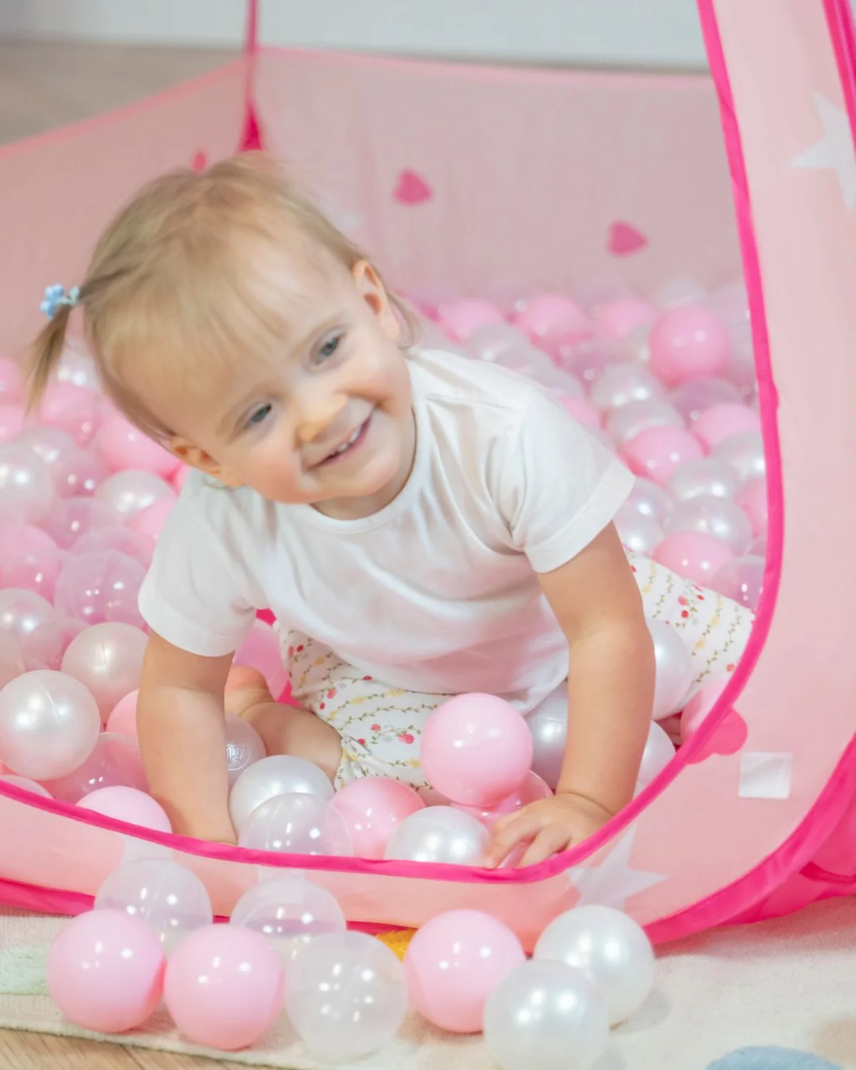 Kind in einem rosa Spielzelt mit Bällen