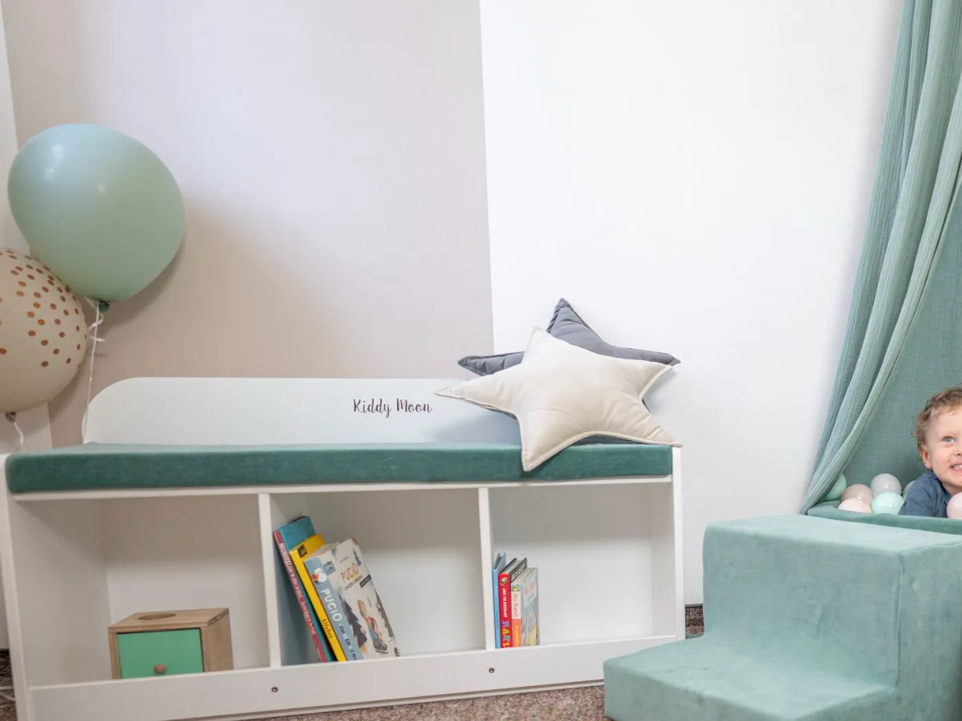 Weiße KiddyMoon Sitzbank mit offenen Fächern für Bilderbücher und einem mintgrünen Sitzkissen